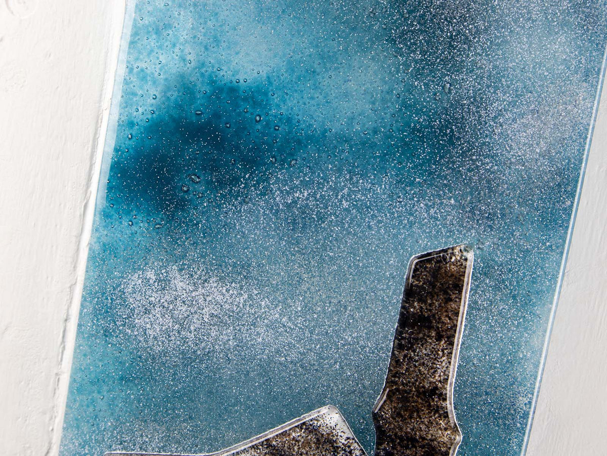 Colour details on a fused glass tin mine wall panel set against a moody dark sky, creating a soft Cornish inspired piece of wall art. 
