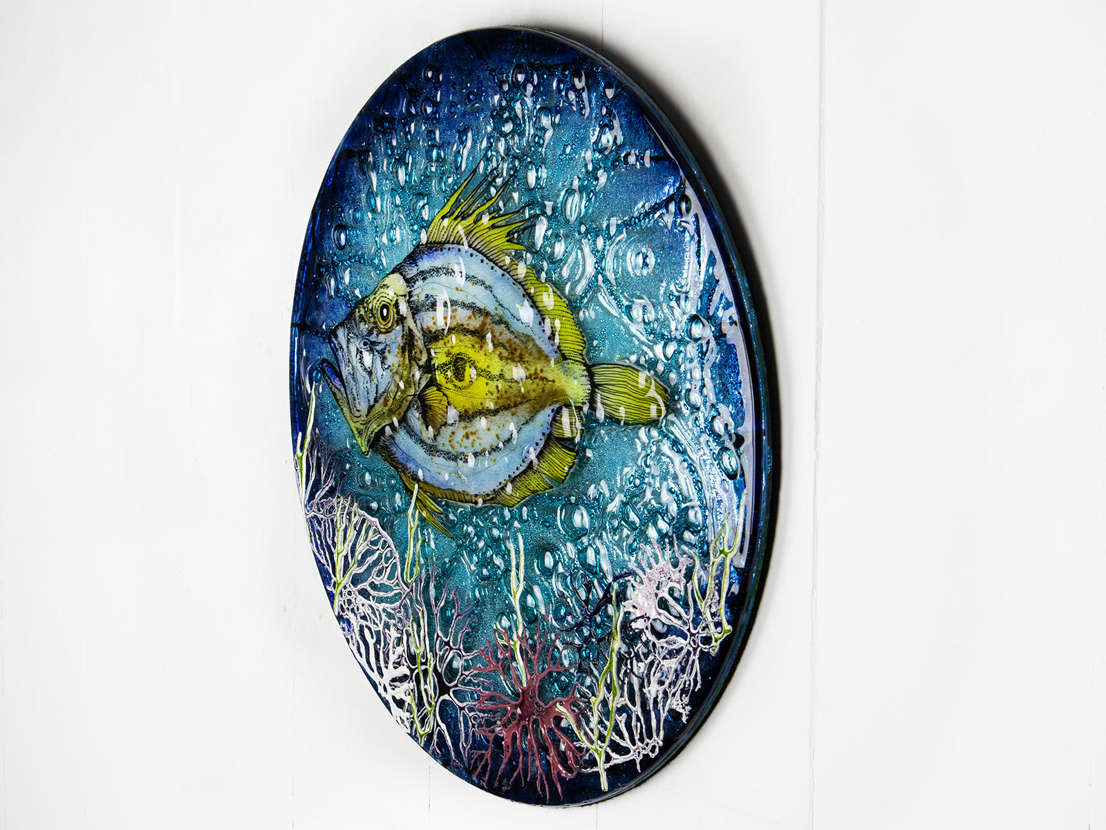 Side image of a round fused glass wall panel, with hand-painted john dory design in vibrant organic colours and textures. 
