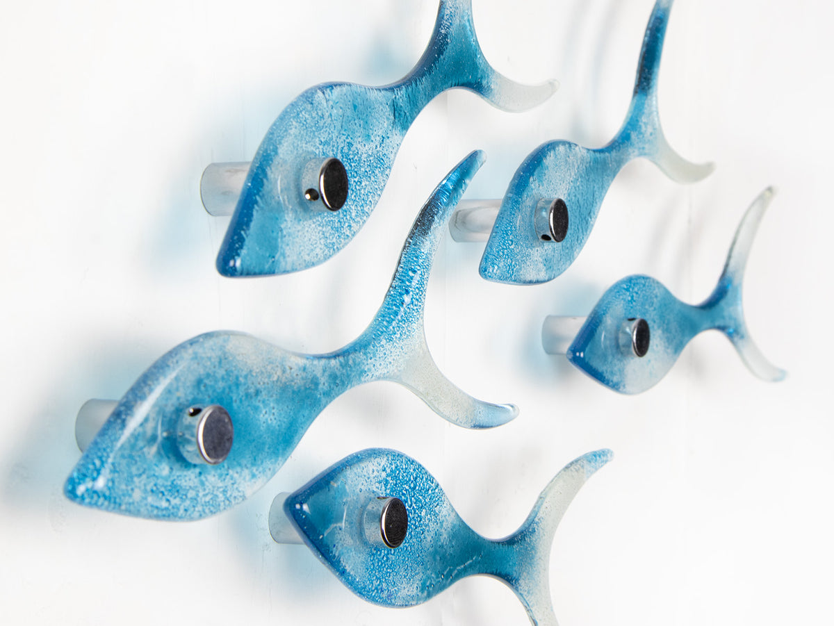 Side image of five fused glass fish, handmade in soft coastal blues, creating an ocean inspired wall art display.