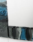 Details on a fused glass oblong mirror, handmade using soft coastal blue tinted and grey glass with delicate texture and a wavy design.