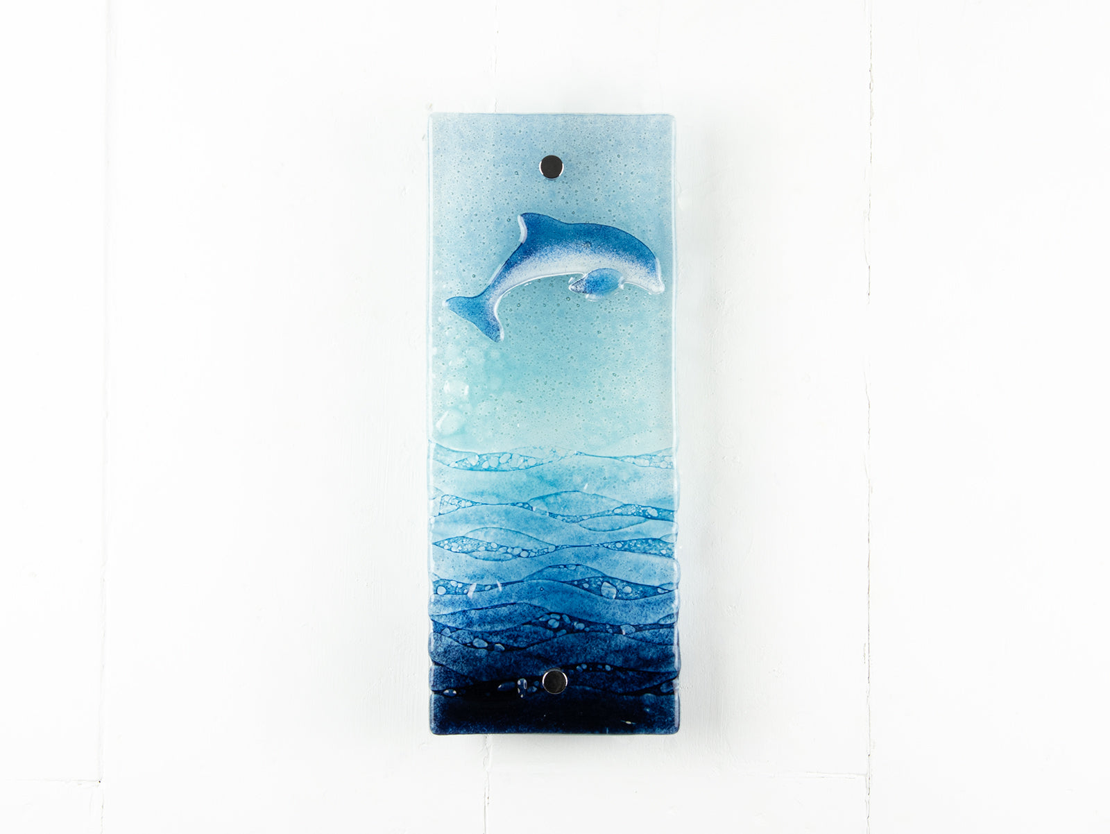 Fused glass wall panel featuring a leaping dolphin and marine blue waves. 