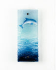 Fused glass wall panel featuring a leaping dolphin and marine blue waves. 