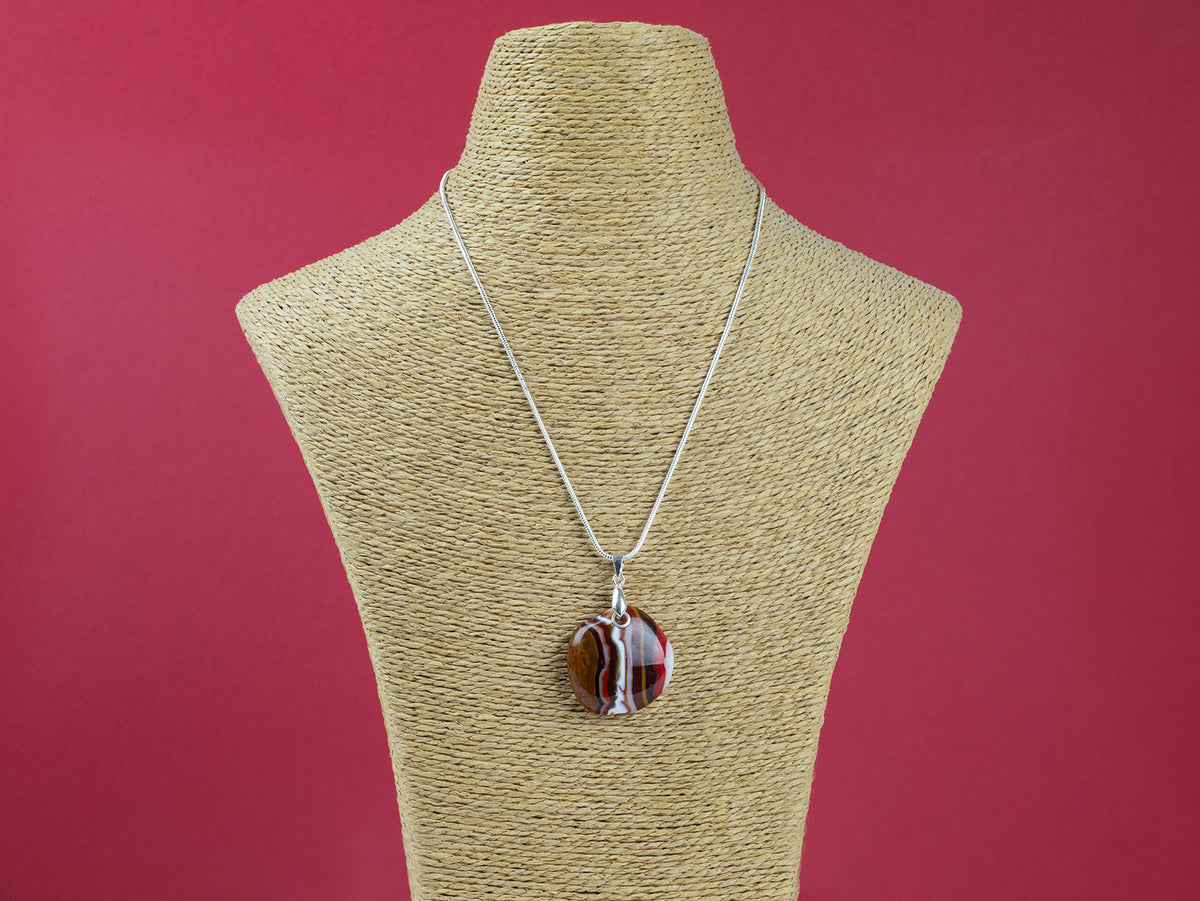 A sterling silver chain necklace with a fused glass pendant featuring a marbled pattern of bright reds and autumnal hues, seen on a mannequin