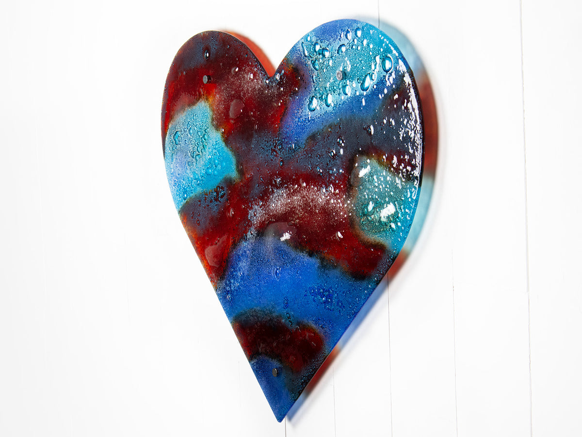 A striking 95cm fused glass hear shaped wall panel handcrafted in Cornish studio in bright reds, aqua blues and lots of textured detailing. 