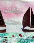 A close up of a fused glass wave panel featuring two metal fish boats and a bright coastal, sunset design with texture. 