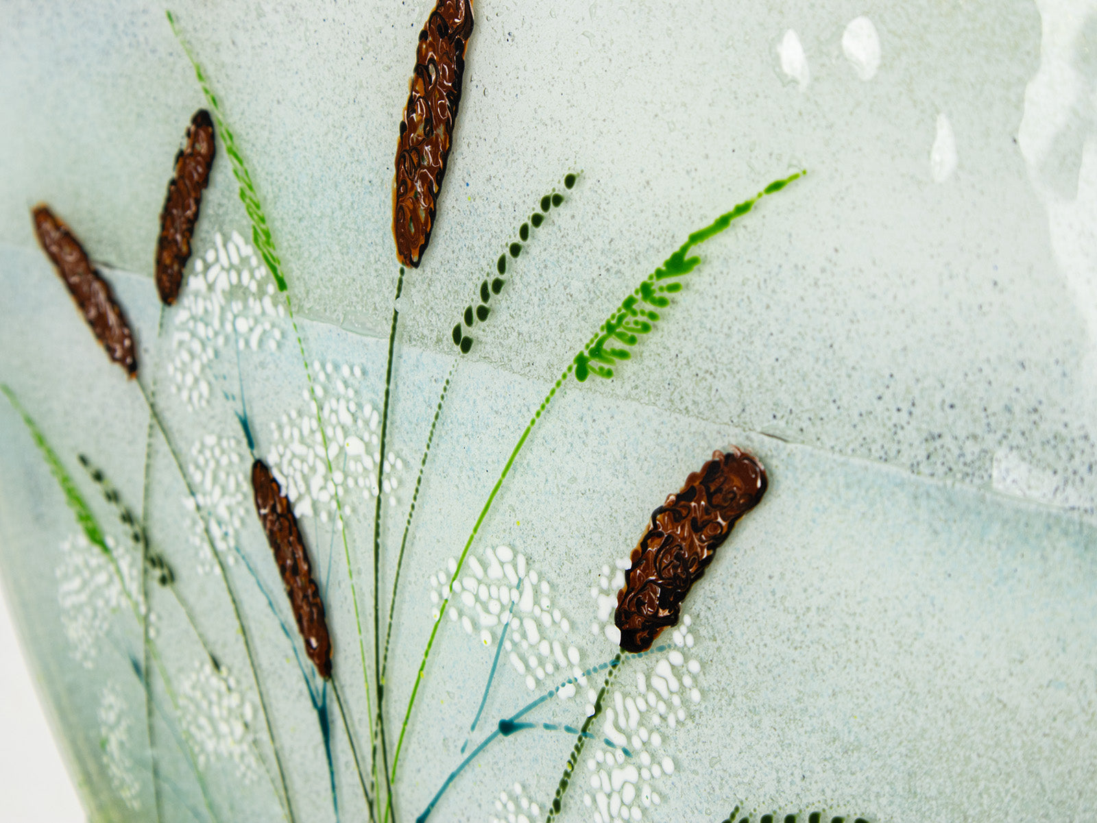 Close up of coastal grasses, hand-painted on a fused glass design with soft ocean colours. 