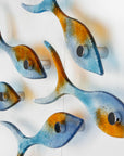 Side image of small display of fused glass fish, individually handmade in sunset orange and sea blue colours. 