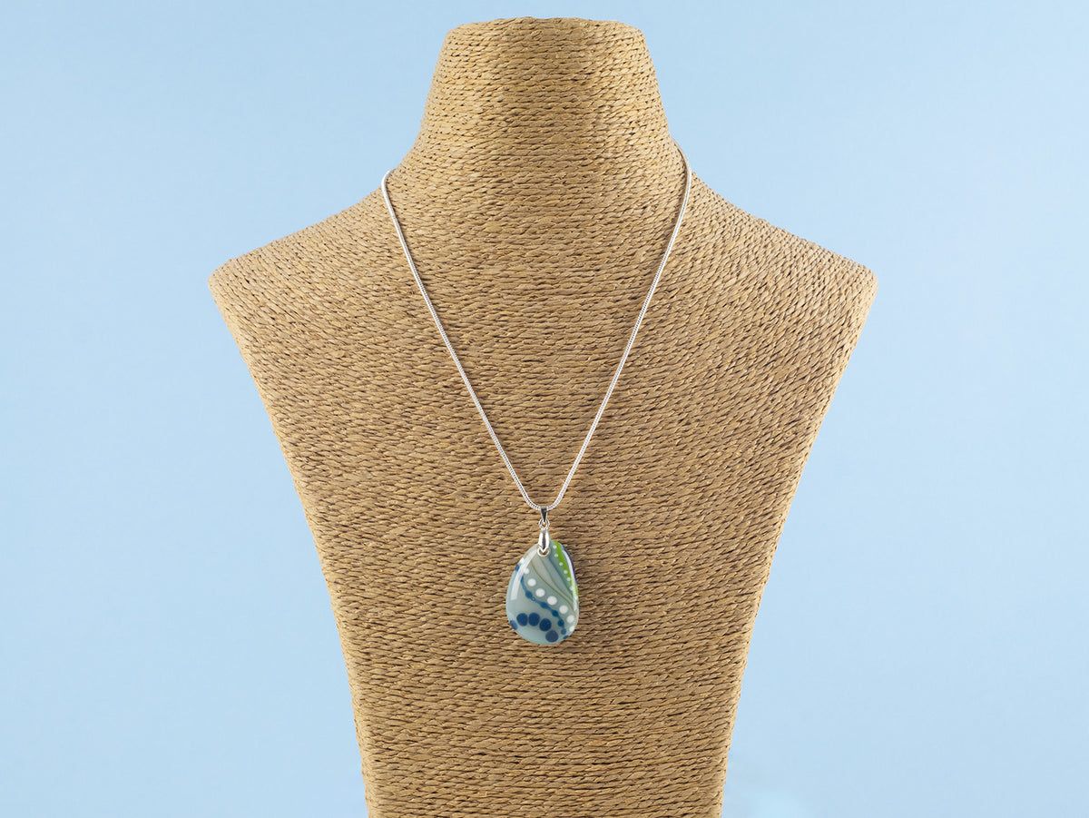 Hung on a Signature by Jo Downs fused glass pendant necklace, handmade in a botanical design and ocean colours with a sterling silver chain and fittings, a striking piece of wearable handcrafted art.