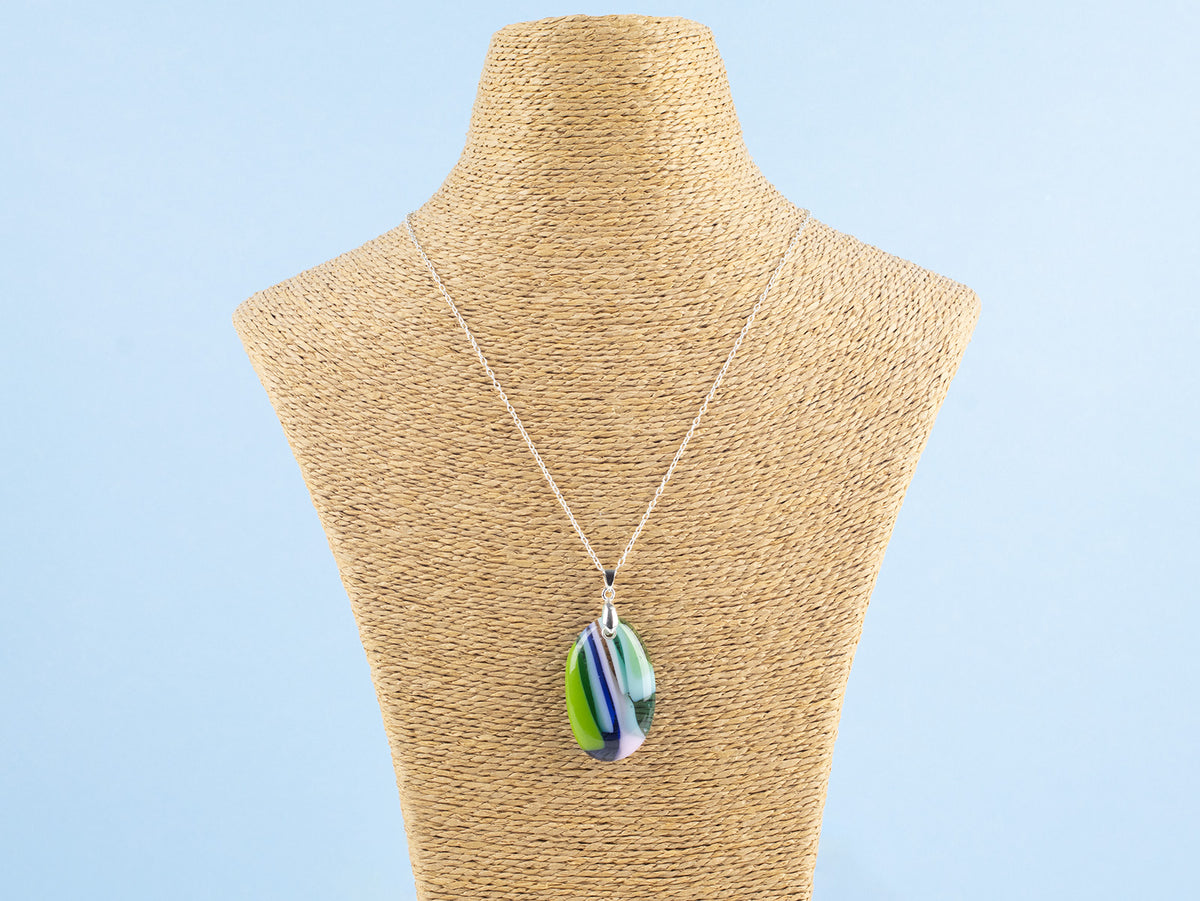 A fused glass pendant necklace, handmade in spring greens, soft pinks and marine blues, hung on a sterling silver chain. 