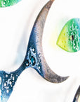 Details of a fused glass ocean shoal of fish, in bright coastal yellows, purples, greens and blues. A vibrant ocean inspired wall art display. 