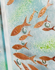 A close-up of a fused glass quintych featuring a soft coastal colour-way with darting copper fish and bubbled detailing. An ocean inspired piece of wall art. 