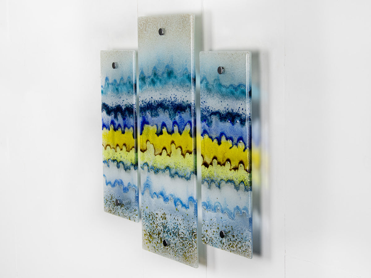 A side image of a fused glass small triptych wall art piece, handmade in coastal, soft, organic colours, inspired by the Cornish beaches.