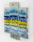 A side image of a fused glass small triptych wall art piece, handmade in coastal, soft, organic colours, inspired by the Cornish beaches.