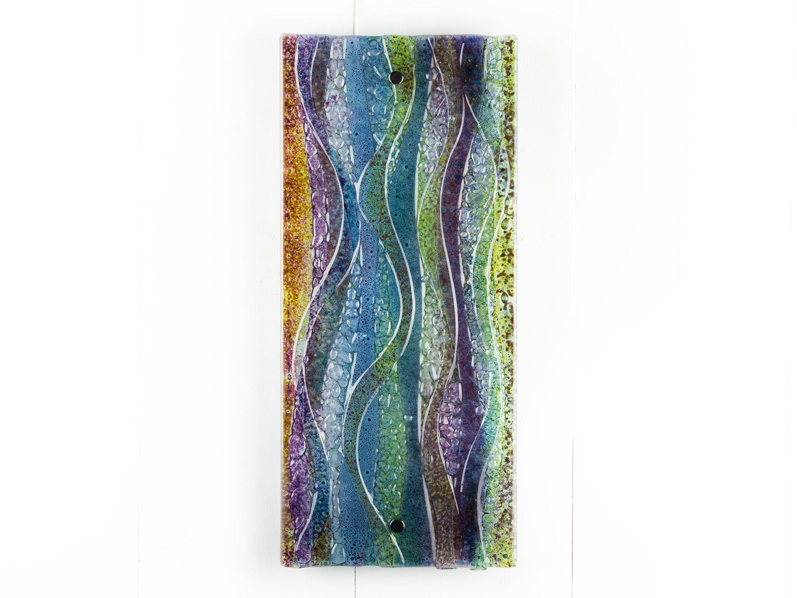 A fused glass wall panel, featuring a wavy design in sea blues, greens and amethyst purples with textured detailing. 