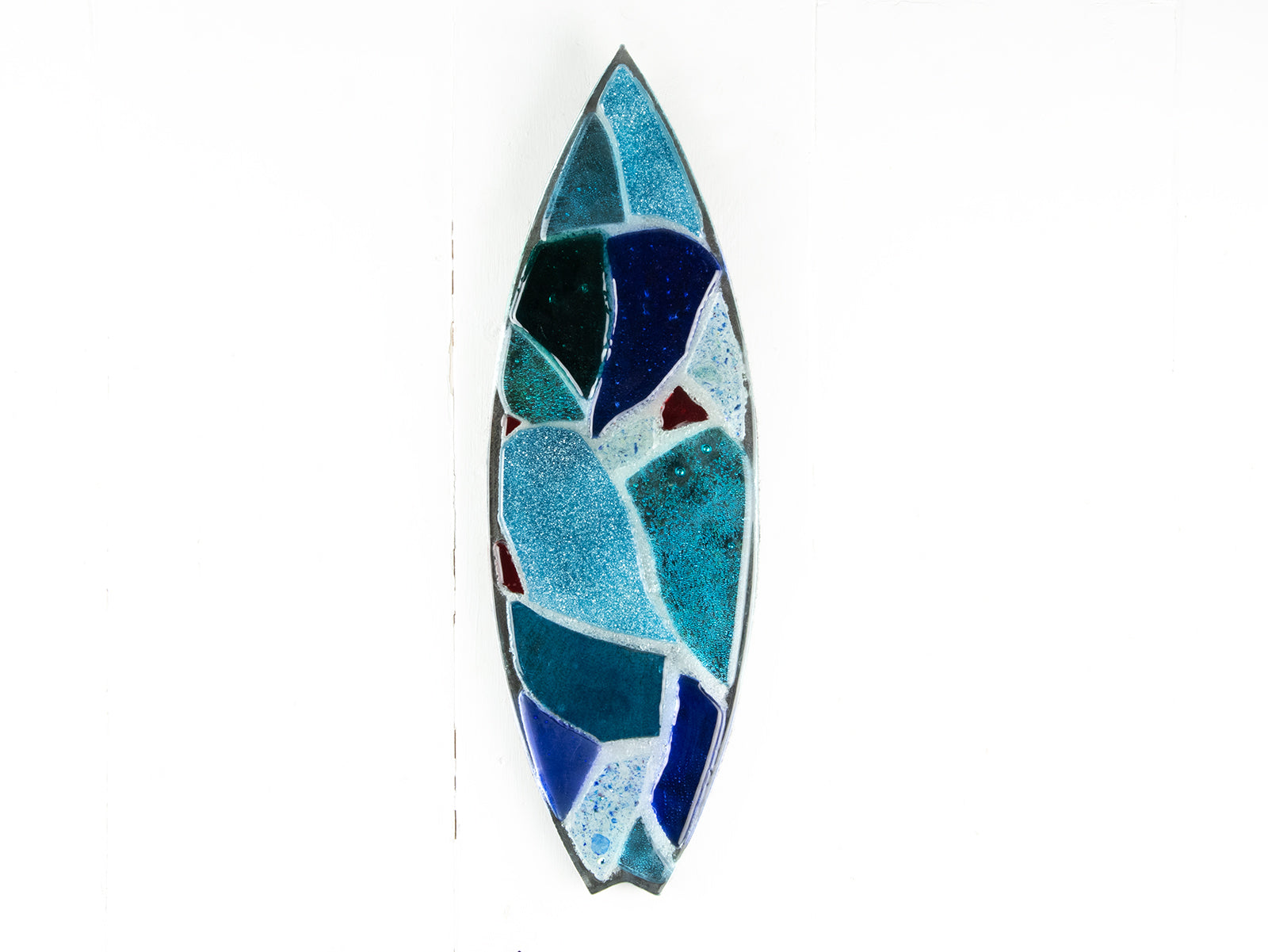 A fused glass surf board wall panel with mirror glass and mosaic inspired design. Handmade in marine blues, creating a lovely coastal piece of art work. 