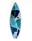 A fused glass surf board wall panel with mirror glass and mosaic inspired design. Handmade in marine blues, creating a lovely coastal piece of art work. 