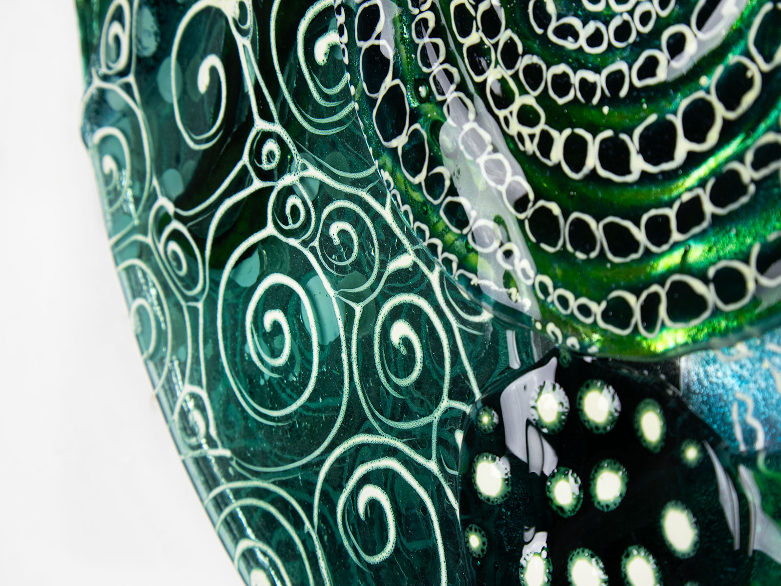 Close up of fused glass round panel, handmade using ocean colours and botanical and organic painted designs. An abstract, coastal inspired piece of wall art. 