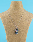 Fused glass pendant necklace handmade in rich coastal and sunset hues, including hand-painted patterns and hung on a sterling silver chain.