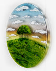 A fused glass round panel featuring a design of the "Nearly Home Trees" located on a hill over-looking the A30. 