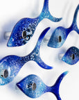 Side image of five fused glass fish in a shoal shape in coastal blues. Handmade ocean inspired wall art.