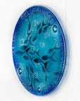 A side view of a round fused glass wall panel featuring hand-cut glass fish and bubbles, designed in a marine blue colour-way.