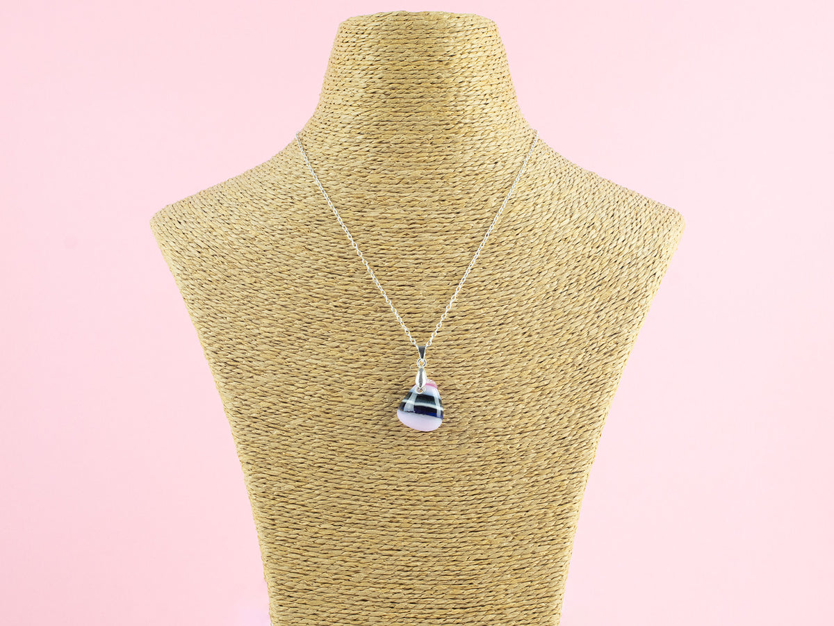 A fused glass pendant necklace, handmade in rose pinks, with dark blues hues, hung on a sterling silver chain.  