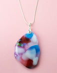 A sterling silver chain necklace with a fused glass pendant featuring a marbled pattern of soft pinks and delicate blue and red hues.