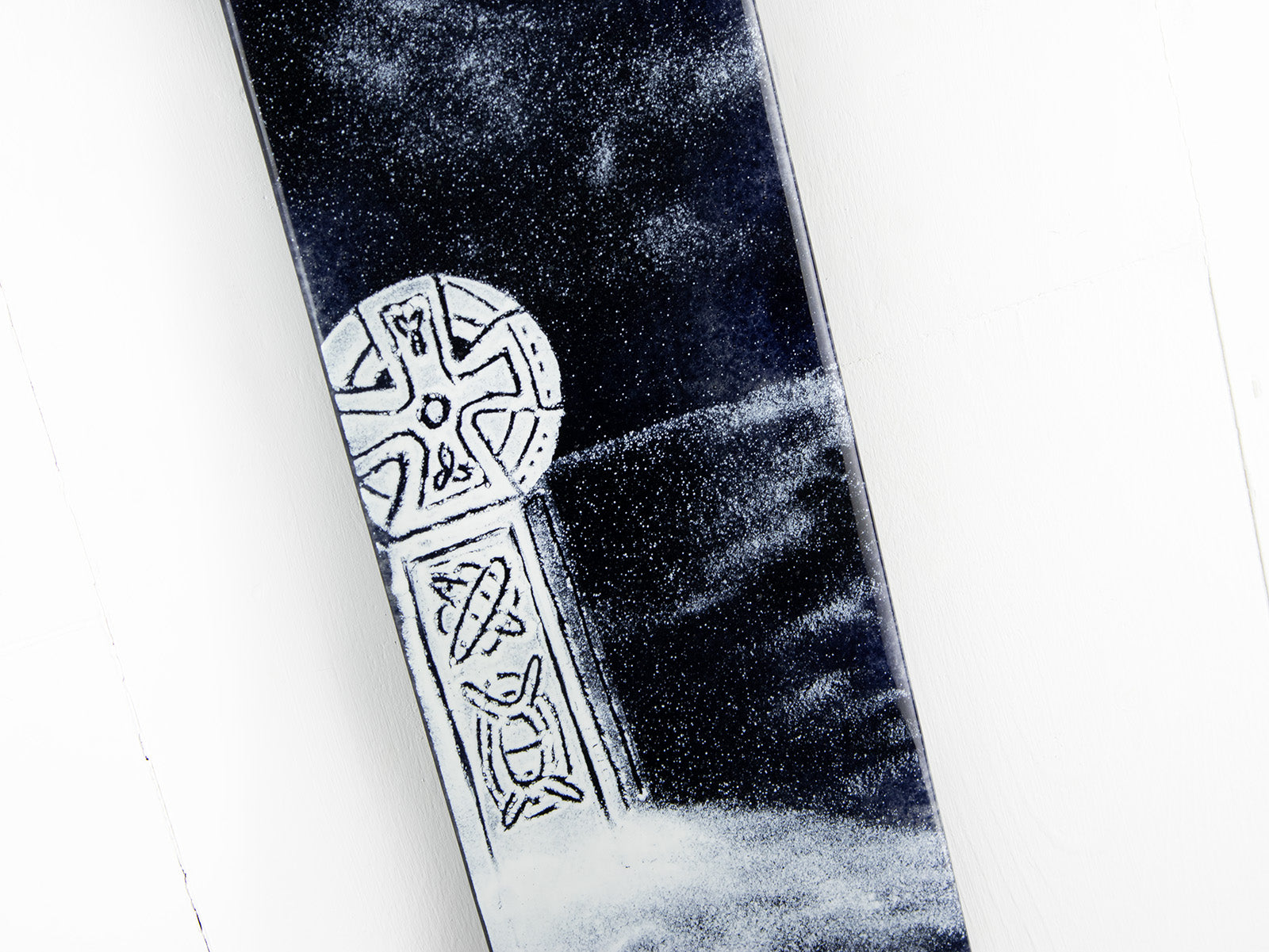 A close up of a fused glass panel featuring a monochrome design of a Cornish Celtic Cross. 