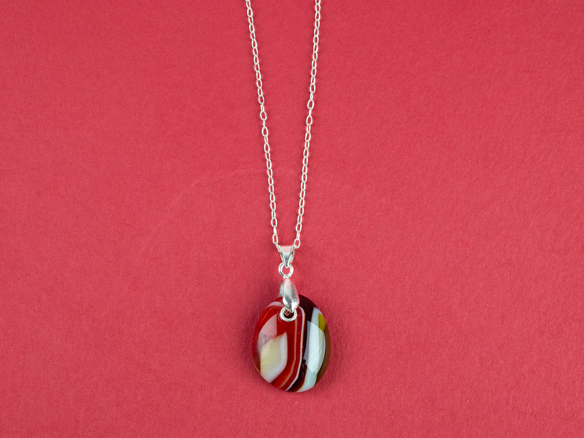 Fused glass pendant necklace, handmade in bright red hues, hung on a sterling silver chain. 