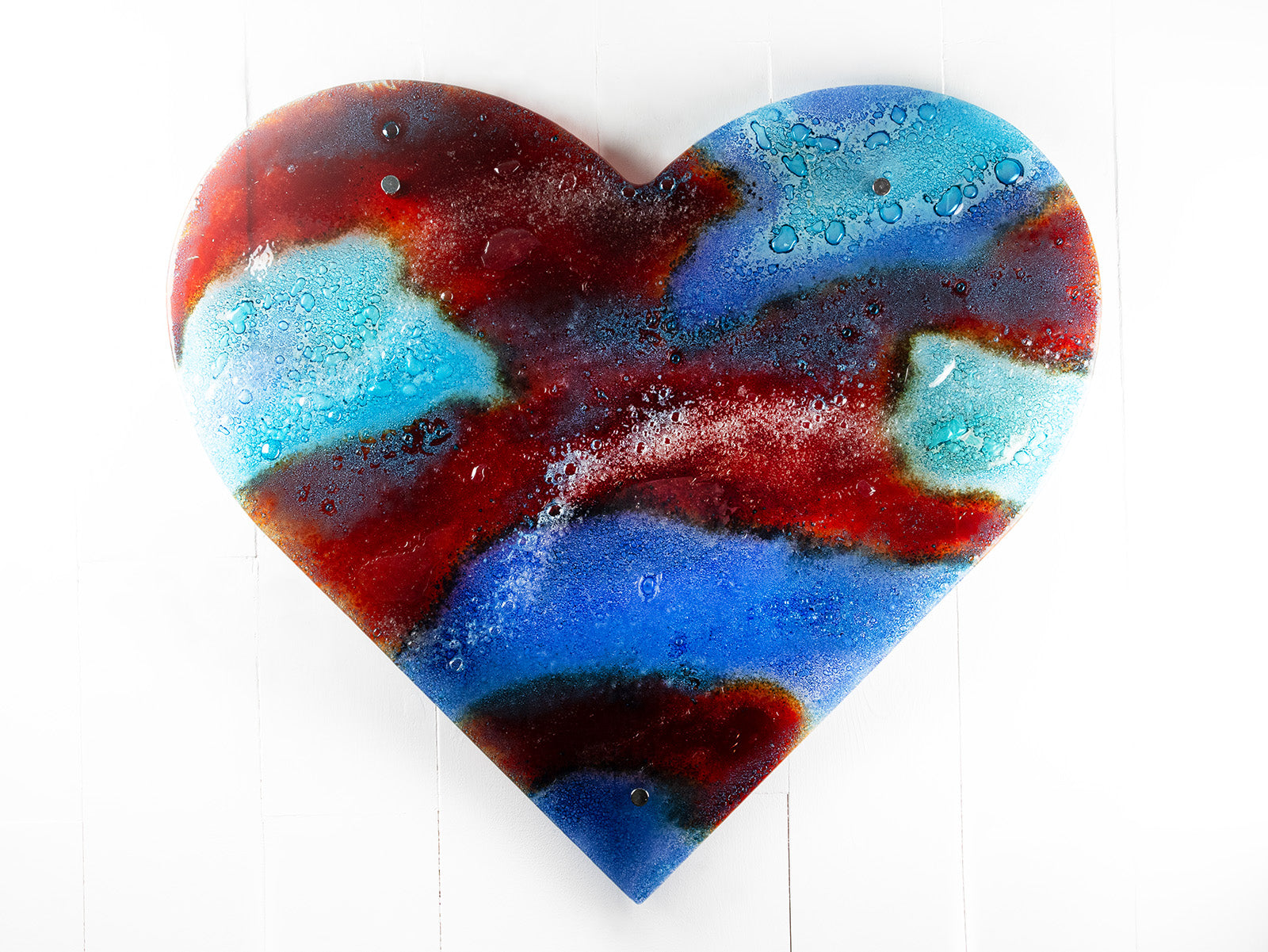 A striking 95cm fused glass hear shaped wall panel handcrafted in Cornish studio in bright reds, aqua blues and lots of textured detailing. 