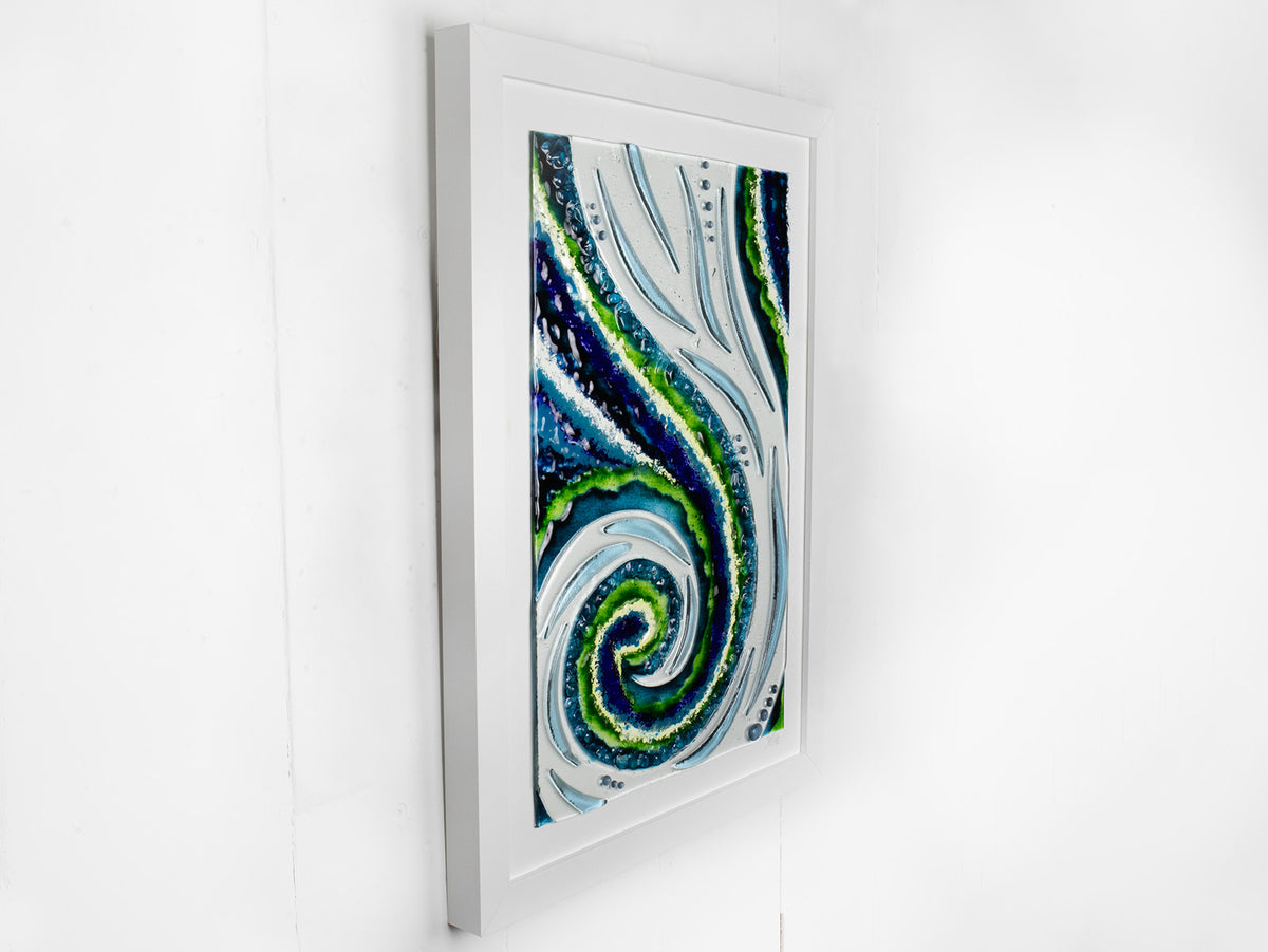 A fused glass large oblong art frame featuring an abstract tidal design in ocean blue and greens with textural detailing. A handmade coastal inspired piece of wall art. 