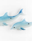 Two blue dolphin wall art panels, handmade i fused glass, designed in soft coastal blues and whites. 