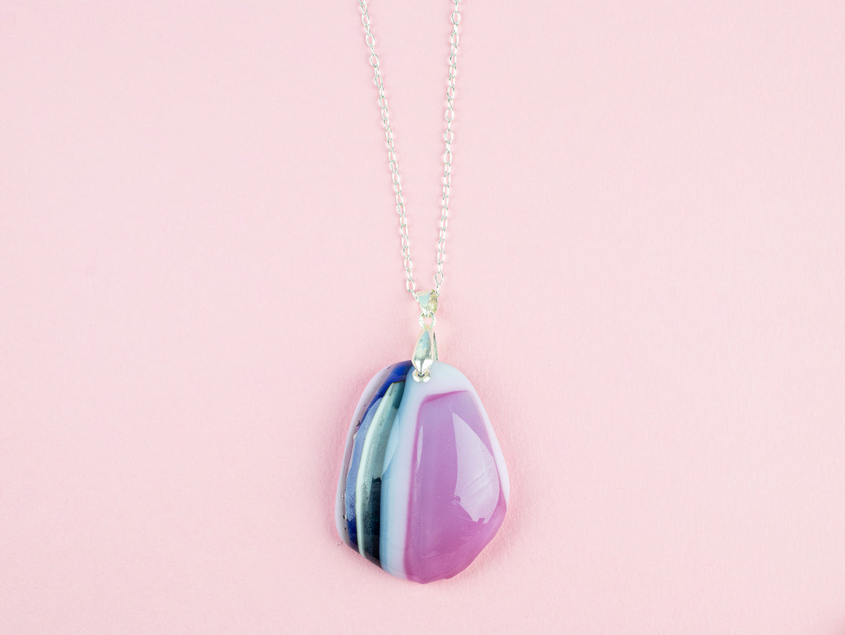 A fused glass pendant necklace handmade in rose pink hues, hung on a sterling silver chain. 