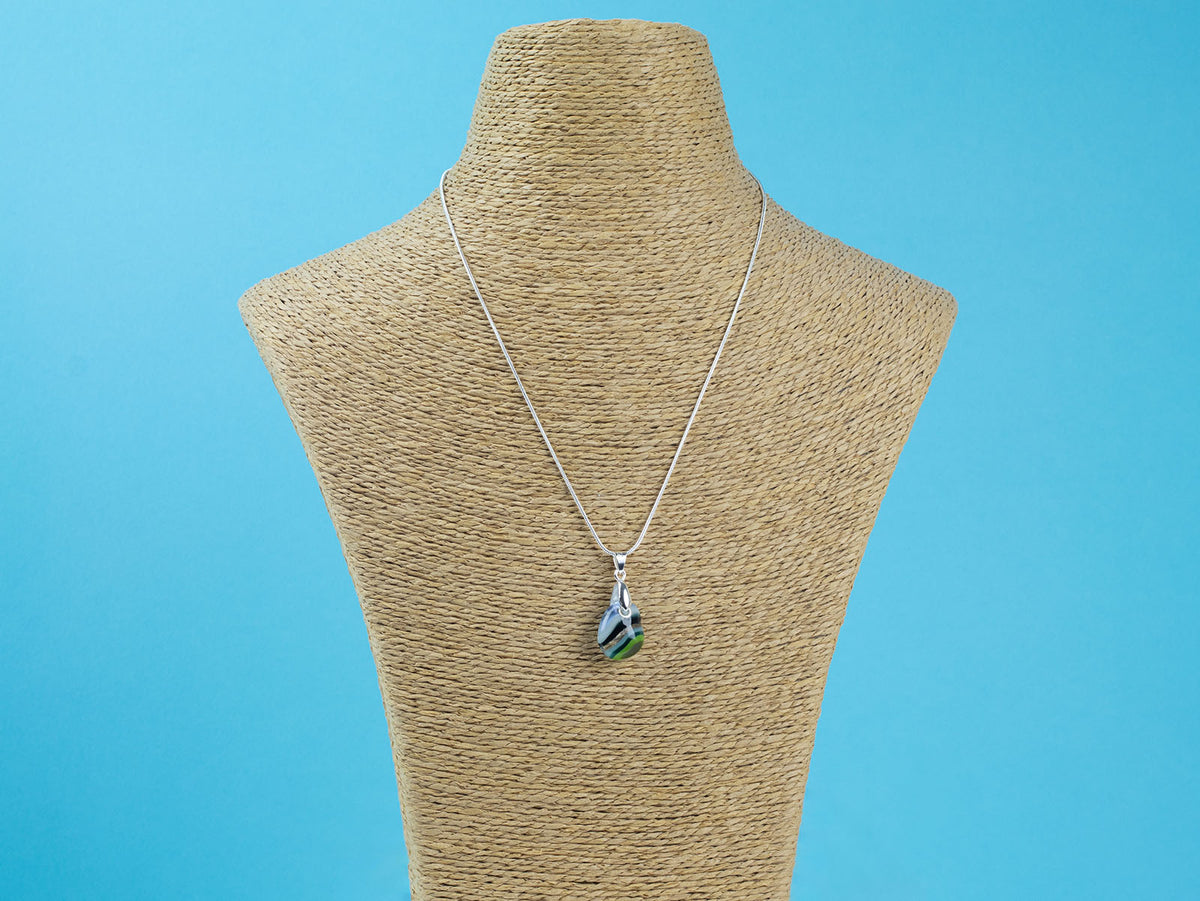 A sterling silver chain necklace with a teardrop-shaped fused glass pendant handmade featuring a ocean blues and sea greens in a marbled design seen on a mannequin. 