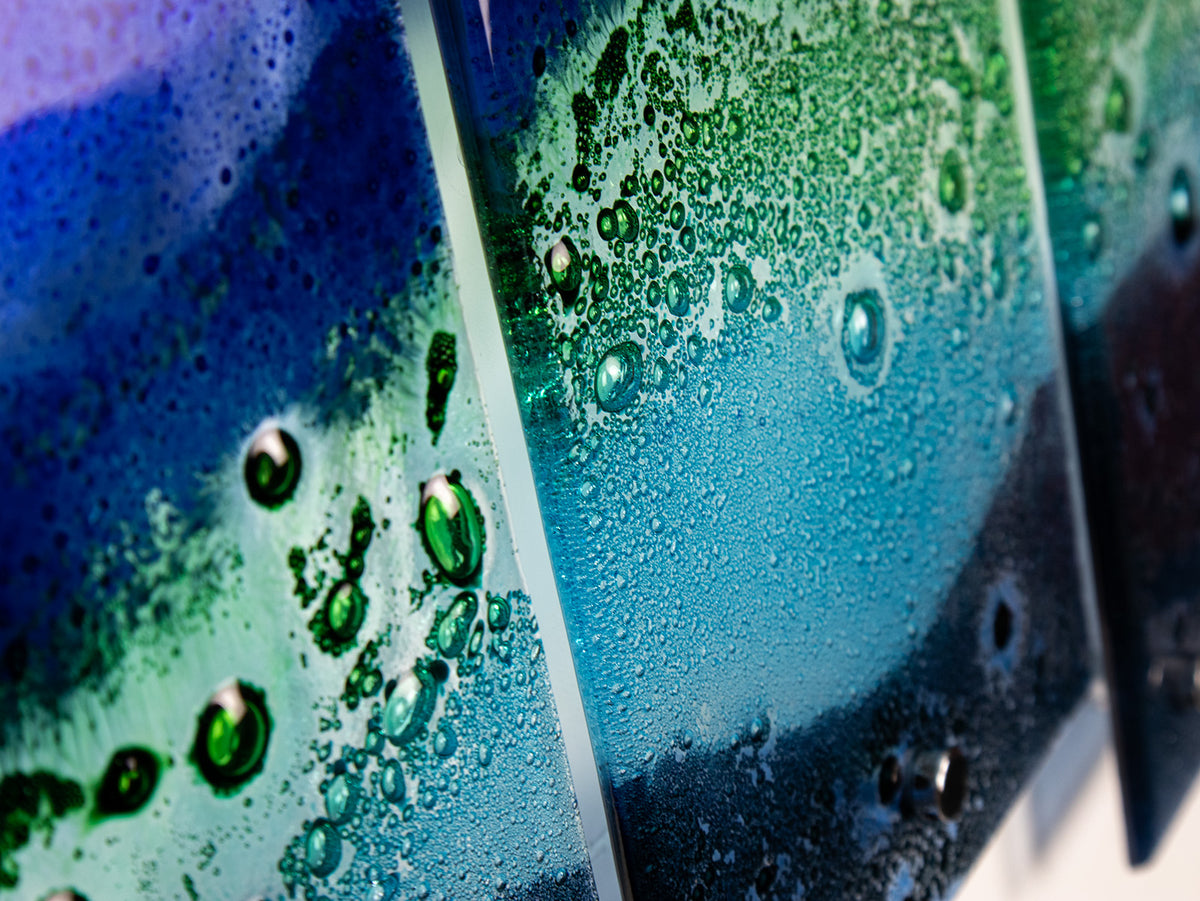 A close up of a fused glass quintych featuring an ocean blue colour-way, inspired by the coast.