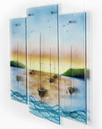 A side image of a fused glass triptych depicting a serene harbour scene with hand-painted sailboats on blue water under a pastel sky with hills in the distance.