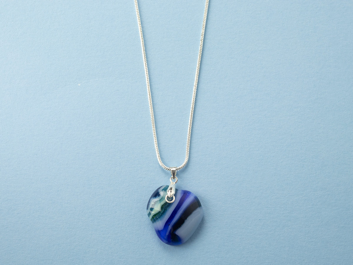 A sterling silver chain necklace with a round fused glass pendant featuring an aqua, blue design, handmade in coastal colours. 