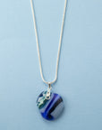 A sterling silver chain necklace with a round fused glass pendant featuring an aqua, blue design, handmade in coastal colours. 