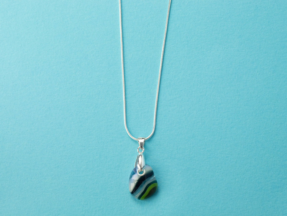 A sterling silver chain necklace with a teardrop-shaped fused glass pendant handmade featuring a ocean blues and sea greens in a marbled design 