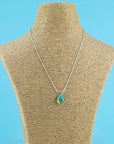 Fused glass small pendant necklace, handmade in ocean blue and green hues, hung on a sterling silver chain. 
