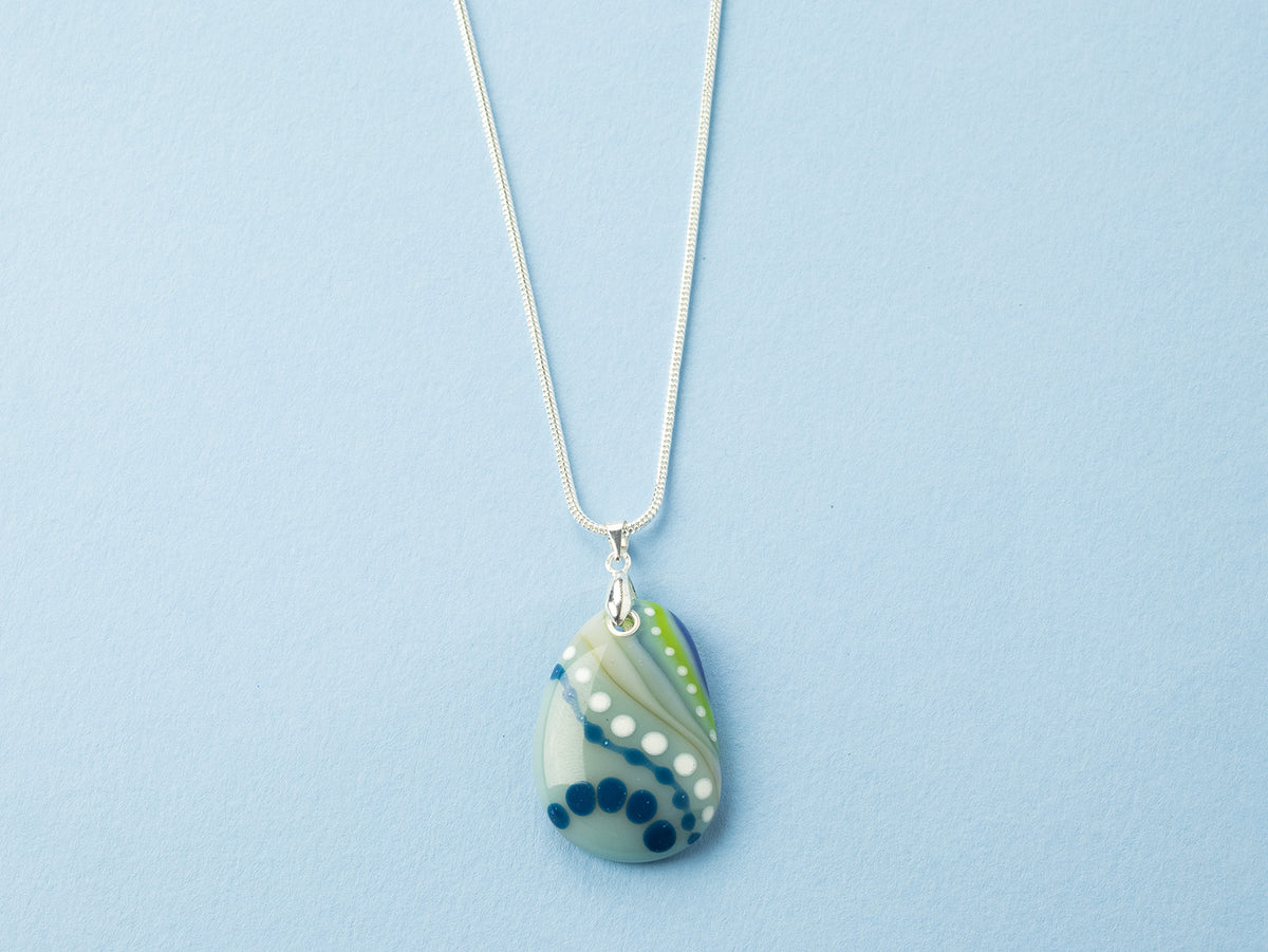 A Signature by Jo Downs fused glass pendant necklace, handmade in a botanical design and ocean colours with a sterling silver chain and fittings, a striking piece of wearable handcrafted art.