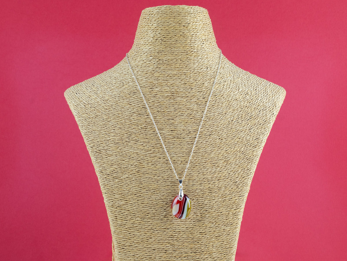 Fused glass pendant necklace, handmade in bright red hues, hung on a sterling silver chain.