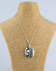 A fused glass pendant necklace, handmade in soft coastal and organic hues, with hand-painted botanical patterns, hung on sterling silver chain. 