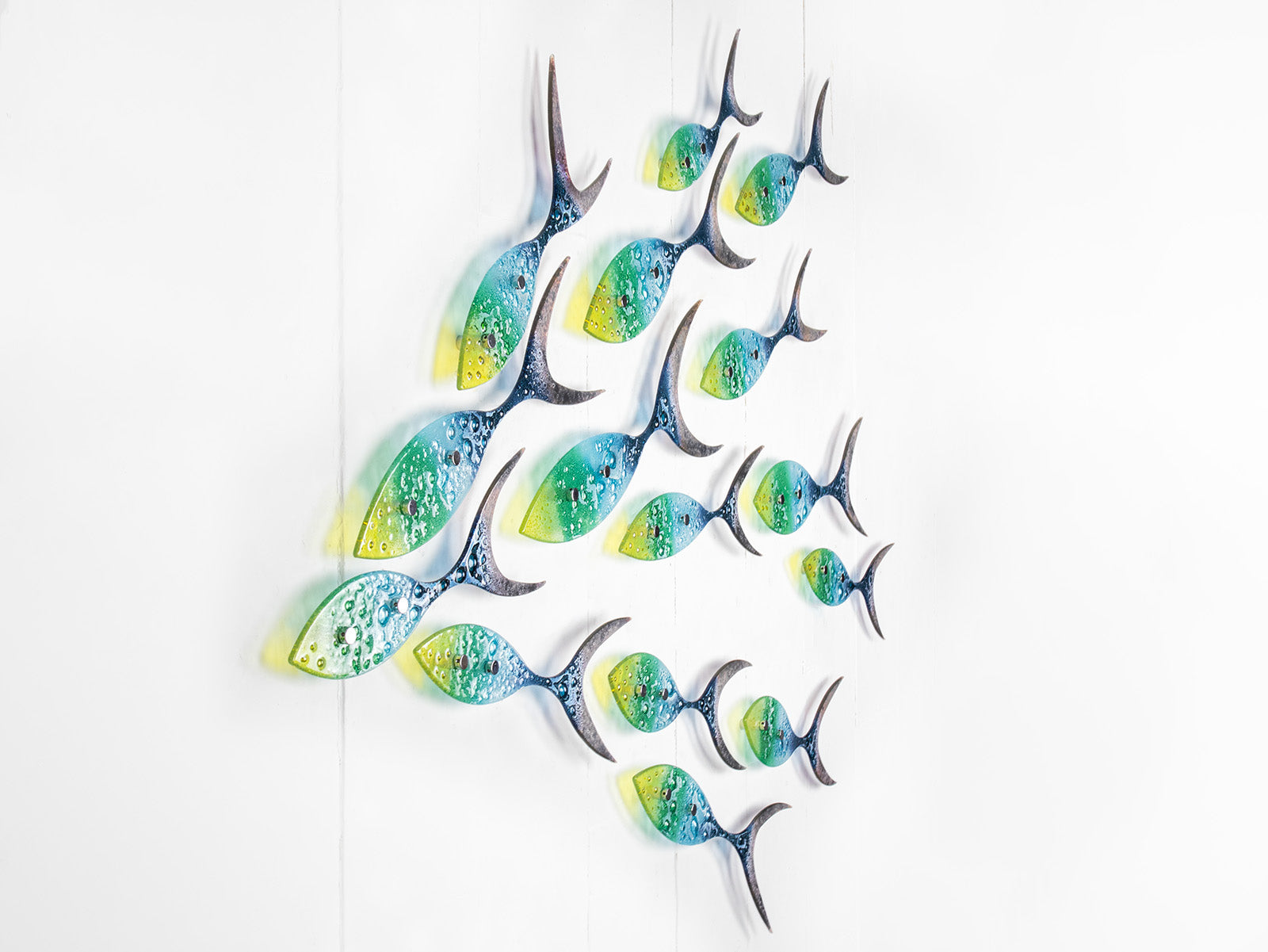 Fused glass ocean shoal of fish, in bright coastal yellows, purples, greens and blues. A vibrant ocean inspired wall art display. 