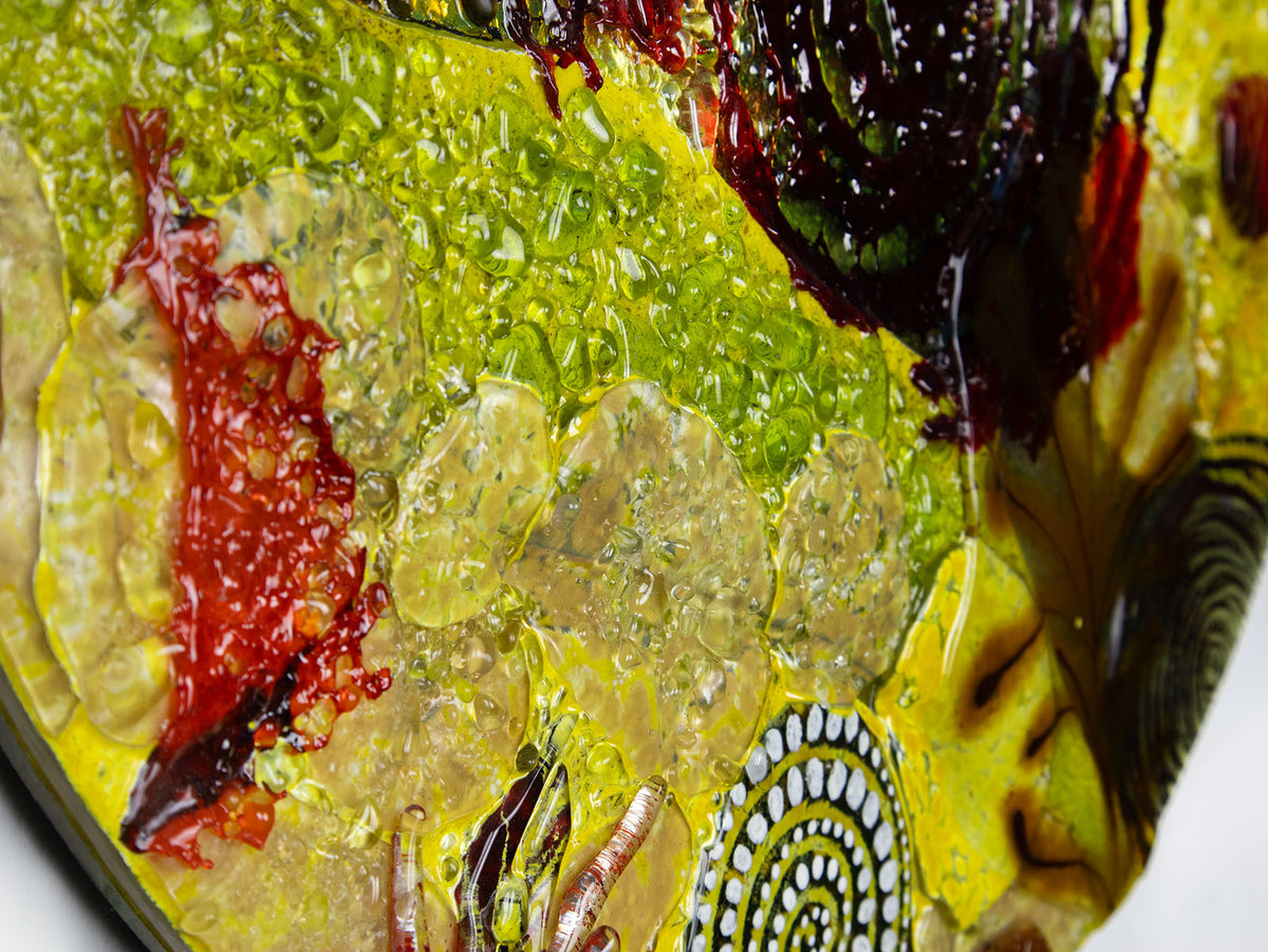 Close up of a fused glass round panel featuring organic autumn inspired patterns and shapes, in a vibrant yellow colour-way, handmade and inspired by the autumnal season. 