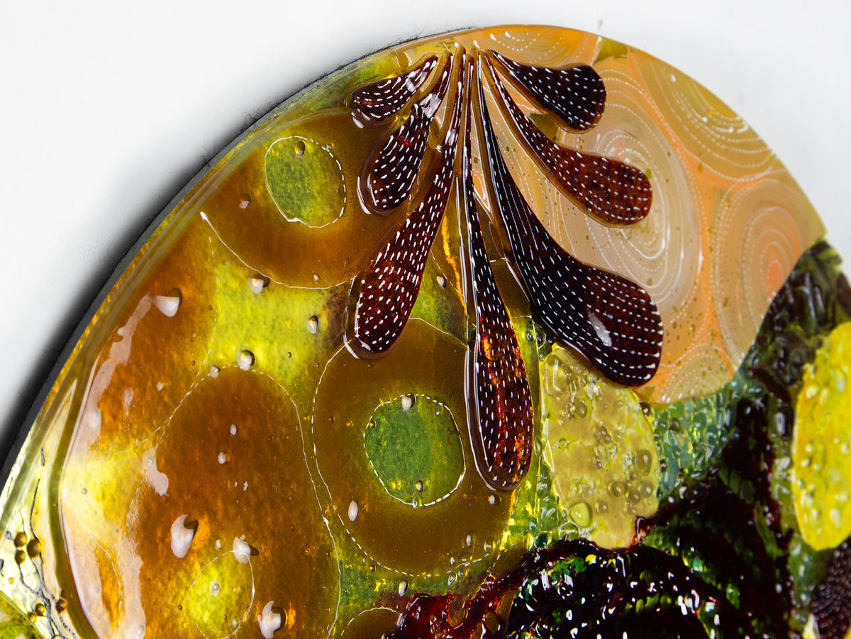 A fused glass round panel featuring organic autumn inspired patterns and shapes, in a vibrant yellow colour-way, handmade and inspired by the autumnal season. 