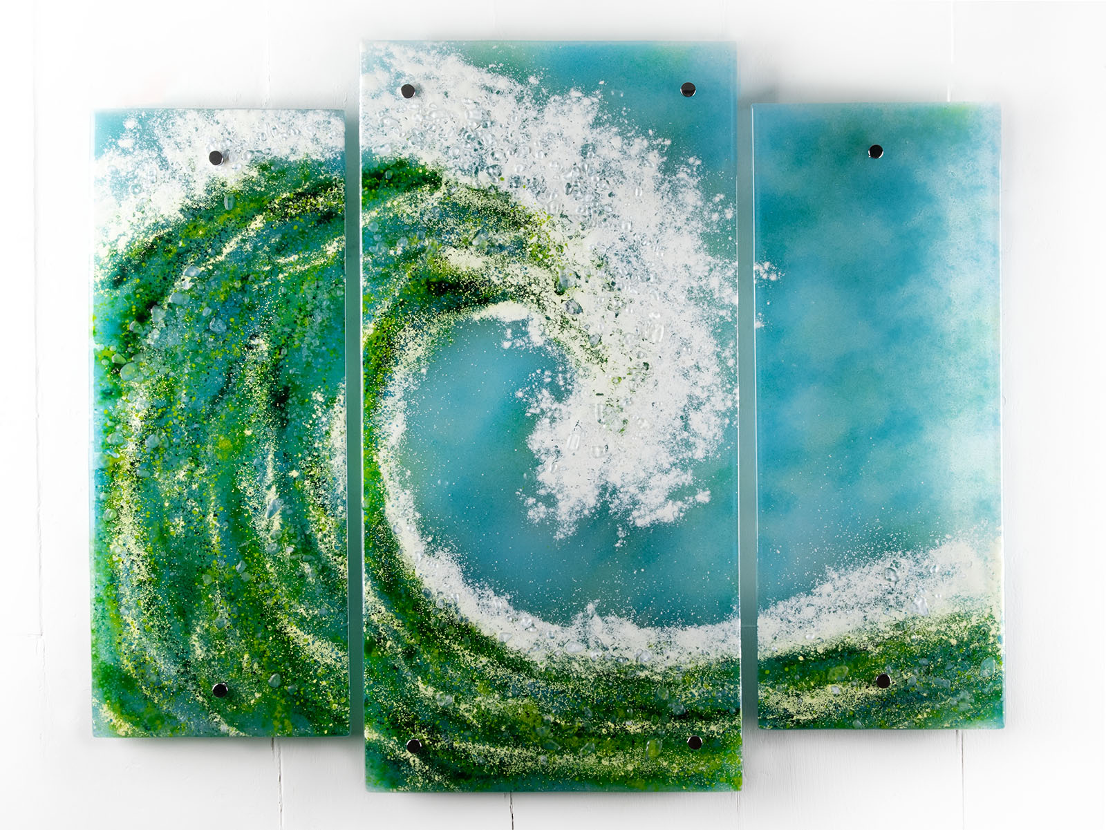 A fused glass triptych featuring a giant ocean wave, with aqua and sea green colours and white texture. 
