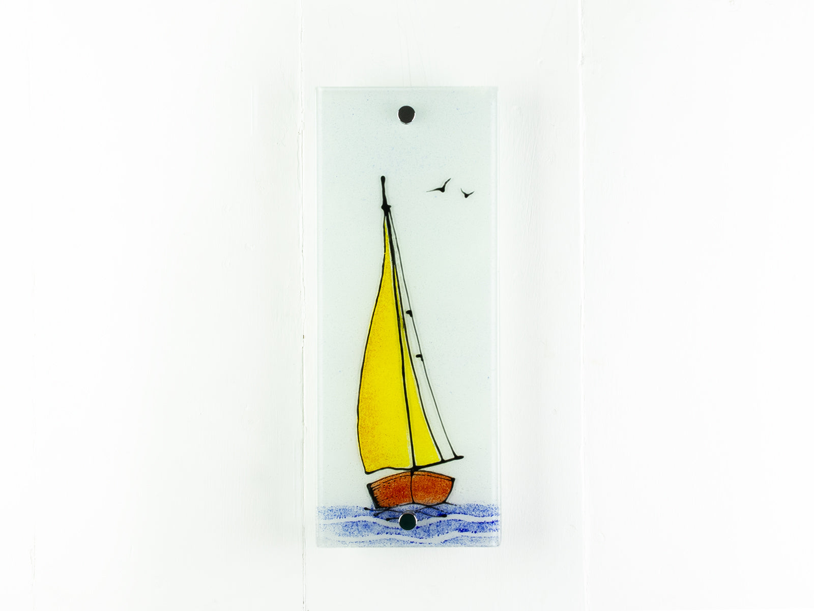 Fused glass wall panel with a sail boat design featuring bright yellow sails and soaring birds. 
