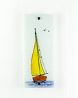 Fused glass wall panel with a sail boat design featuring bright yellow sails and soaring birds. 