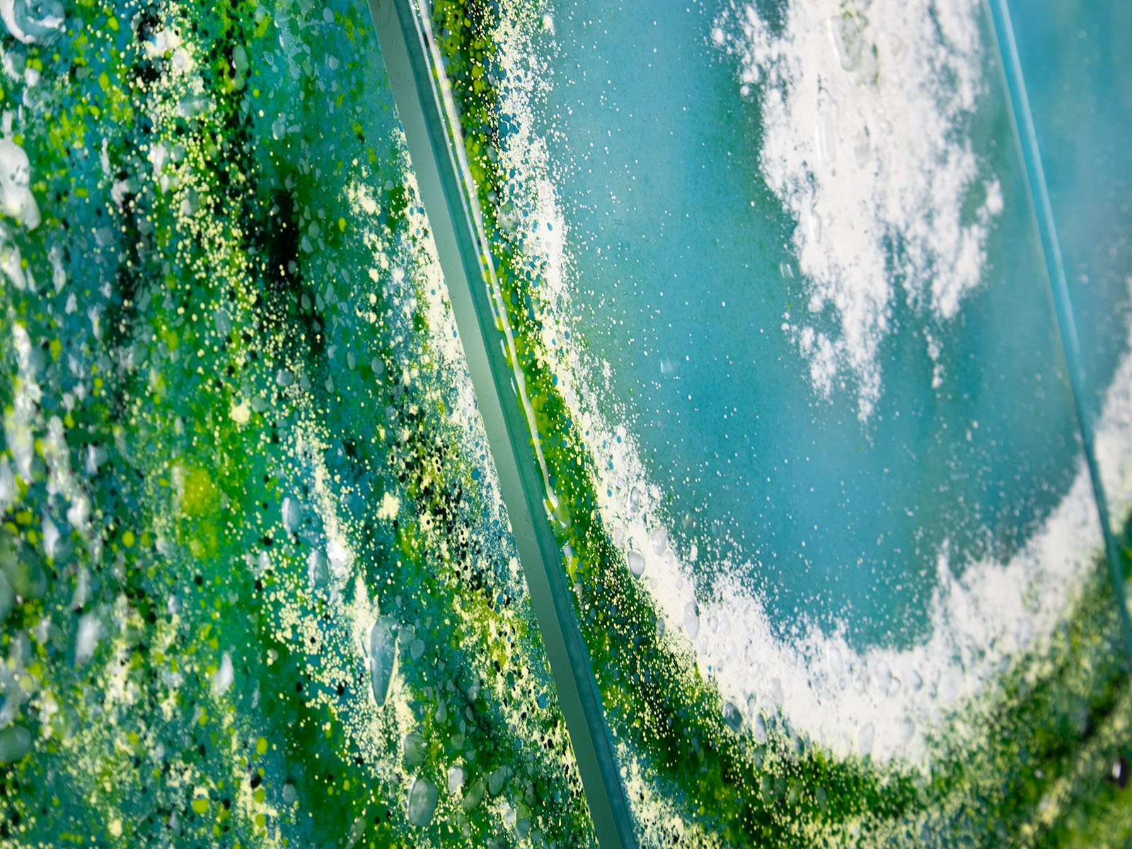 Textured detailing on a fused glass triptych featuring a giant ocean wave, with aqua and sea green colours and white texture. 
